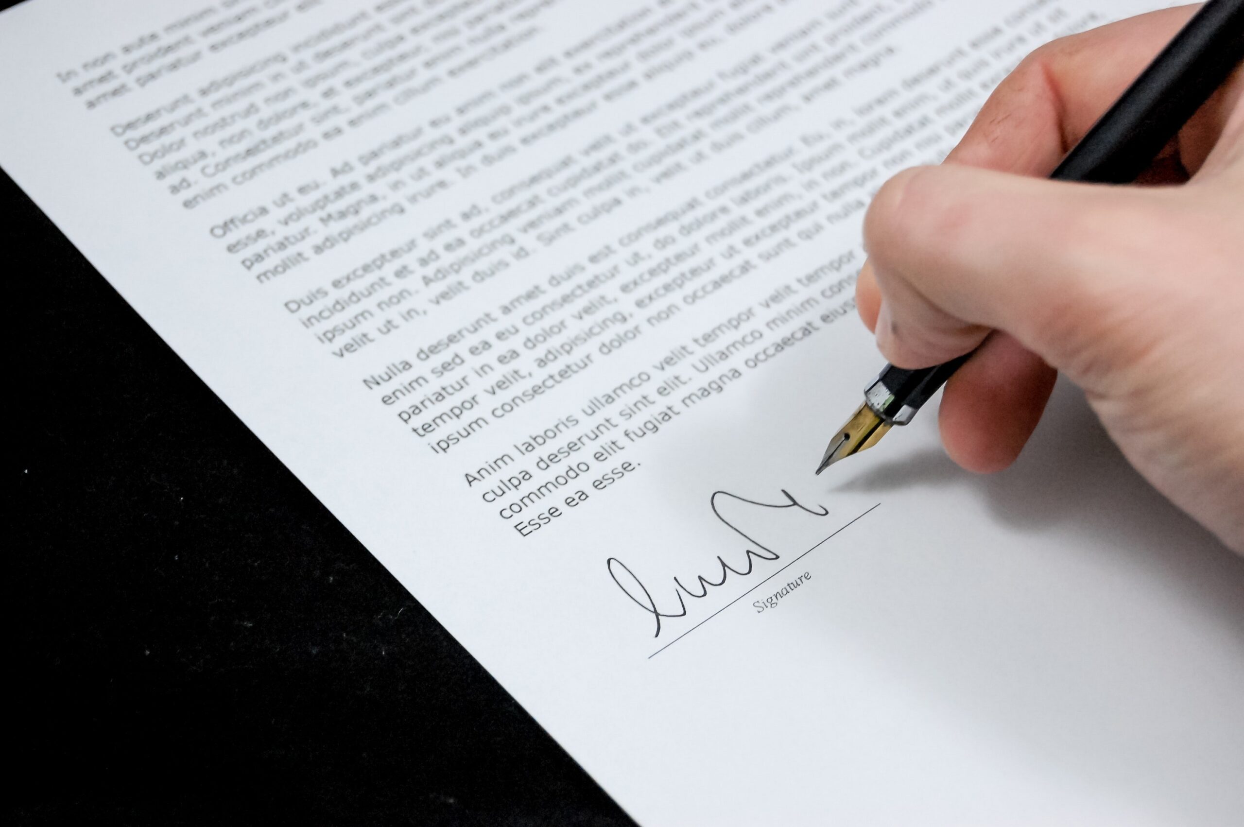 Hand holding a pen signing a letter